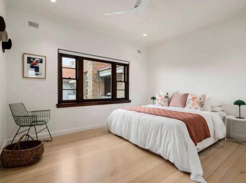 a white bedroom with a large bed and a window at ‘Lynton-Sur-Mer’ - Beachside Apt with Heating in Melbourne