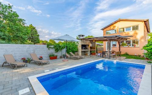 a swimming pool with chairs and an umbrella next to a house at Villa Iness Medulin in Medulin