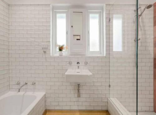 a white bathroom with a sink and a bath tub at ‘Lynton-Sur-Mer’ - Beachside Apt with Heating in Melbourne