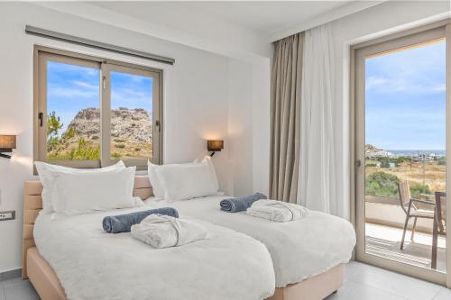 two beds in a hotel room with a large window at KOUROS STONE SUITES in Haraki