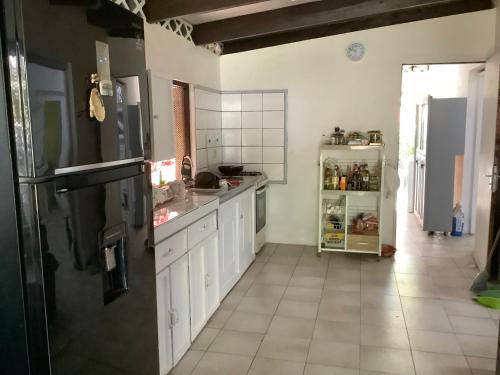 a kitchen with white cabinets and a black refrigerator at Bora Red Hibiscus Lodge in Bora Bora