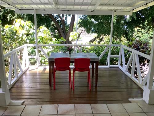 a wooden table and two red chairs on a porch at Bora Red Hibiscus Lodge in Bora Bora