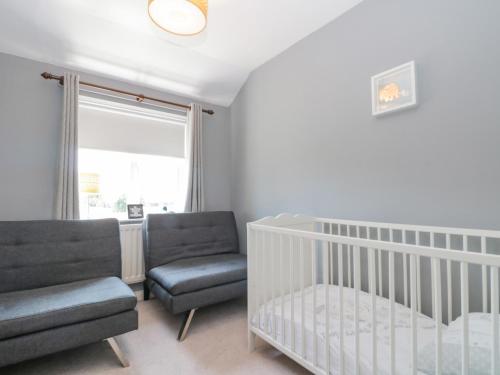 a baby room with a crib and a chair at Sutton Court in Thirsk