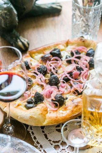 a pizza with olives and onions on a table at Karja Accommodation in Haapsalu