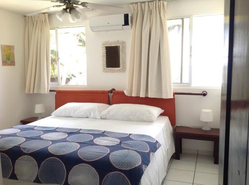 ein Schlafzimmer mit einem Bett und zwei Fenstern in der Unterkunft La Punta Apartamentos in Cabarete