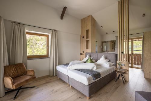 een slaapkamer met een groot bed en een stoel bij Hotel Oberwirt in Verano