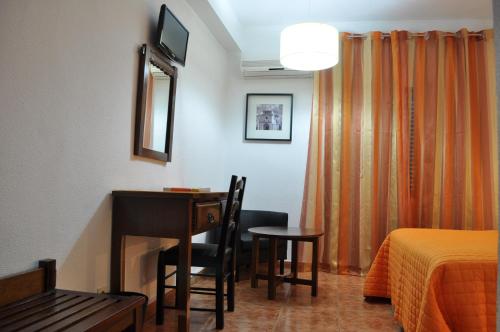 Cette chambre comprend un bureau, un lit et un miroir. dans l'établissement Hotel Brasa, à Elvas