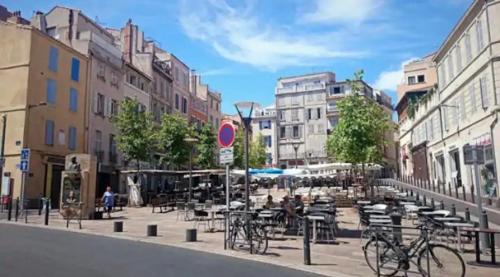 uma rua da cidade com mesas, cadeiras e edifícios em Bienvenue chez vous au Panier ! Appartement classé 1 étoile em Marselha