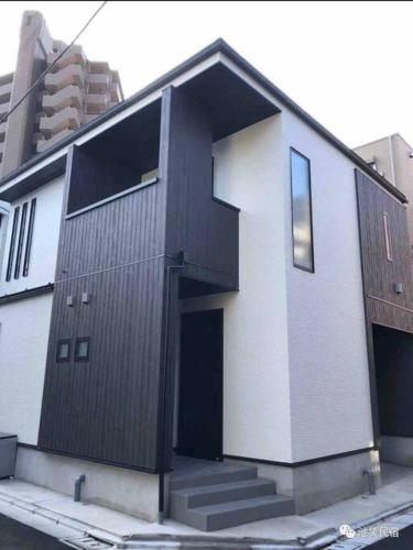 a black and white building with a door and stairs at Uhome Ikebukuro Villa 7 in Tokyo