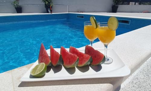 uma bandeja de frutas e dois copos de sumo junto a uma piscina em Holiday Home Gabi em Sibenik