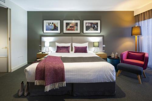 坎培拉的住宿－東方酒店及公寓，一间卧室配有一张大床和一张红色椅子