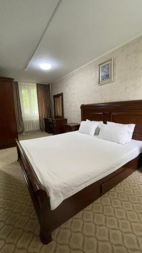 a bedroom with a large bed with white sheets and pillows at PARK HOTEL Uralsk in Uralsk