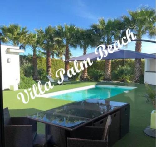 une piscine avec un panneau indiquant villa beach dans l'établissement Villa Palm Beach - Cap d'agde - 450m Plage, au Cap d'Agde