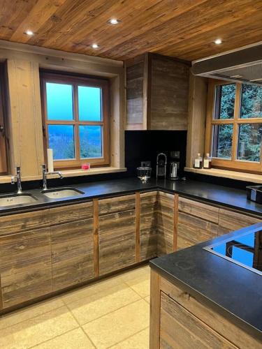 une grande cuisine avec des placards en bois et des comptoirs noirs dans l'établissement Chalet Bellevue 5*, Megeve, à Megève