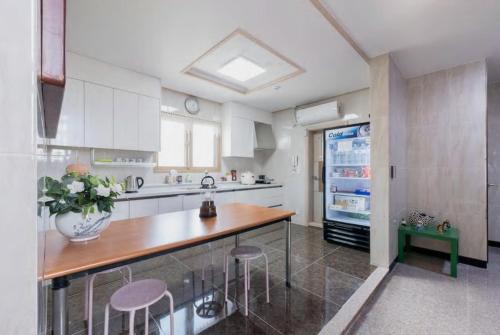 a kitchen with a counter with stools and a refrigerator at Hub Guest House in Incheon