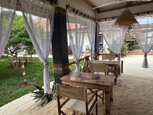 una mesa y sillas bajo una tienda con cortinas en Ocean Breeze Boutique Hotel en Nungwi