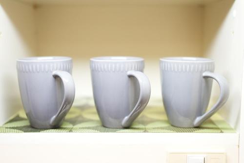three white cups sitting on top of a shelf at Kameari 1108 Budget Stay High Floor Near Station Mall Disney Access in Tokyo