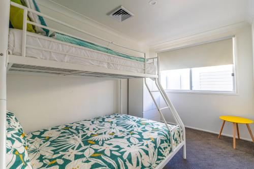 a bedroom with a bunk bed and a yellow table at Cockatoo House in Sussex inlet