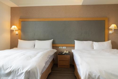 two beds in a hotel room with white sheets at 沐棧行旅-花蓮Muchan Hotel-Hualien in Jian