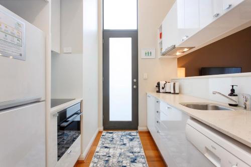 a kitchen with white cabinets and a sink at Luxury Modern Escapia in Fremantle