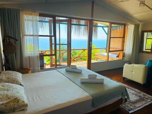 a bedroom with a large bed with a view of the ocean at Honey Hill Faralya Forest Cabins by the Sea in Faralya