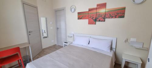 a bedroom with a white bed and a red chair at Happy b&b in Torremaggiore