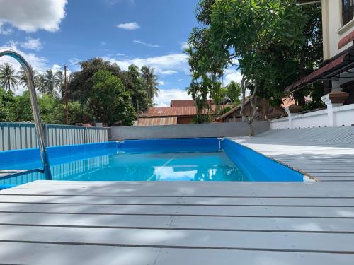 une piscine bleue avec des escaliers en face d'une maison dans l'établissement Vongprachan Backpackers Hostel, à Luang Prabang