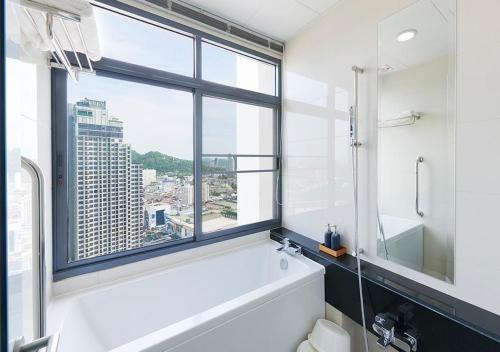Citiresort @sea sriracha في سي راشا: حمام مع حوض أبيض ونافذة