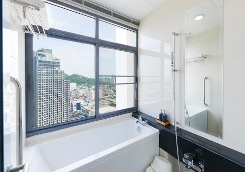 a bathroom with a white tub and a window at Citiresort @sea sriracha in Si Racha