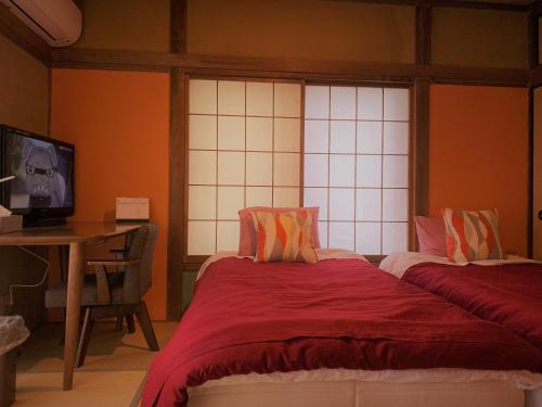 a bedroom with two beds and a desk and a television at アニメーションの起源地にある大泉学園ヴィラ in Katayama