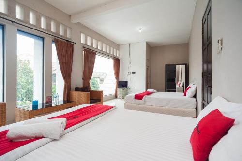 een slaapkamer met 2 bedden en een groot raam bij RedDoorz Syariah near Taman Air Mancur Bogor in Bogor