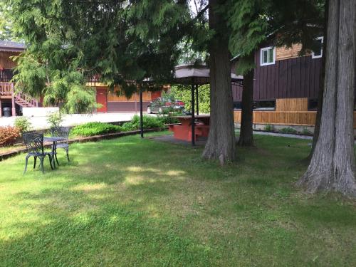 a park with two trees and a table and benches at Copper River Motel in Terrace
