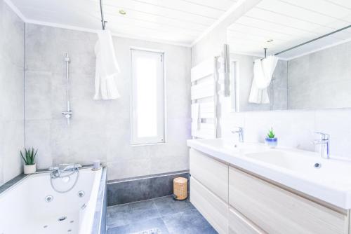a white bathroom with a tub and a sink at A découvrir - L'Emergence in Strasbourg