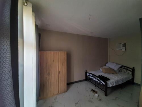 Schlafzimmer mit einem Bett und einem Holzschrank in der Unterkunft Baverlly Home Stay in Cotabato