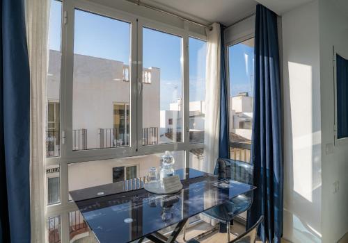 szklany stół i krzesła w pokoju z oknami w obiekcie PLAYA CARIHUELA Apartamentos El CARMEN w mieście Torremolinos