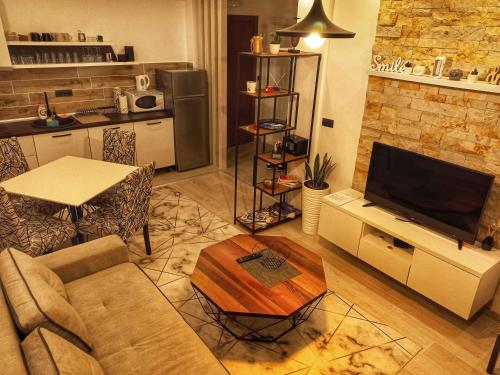 ein Wohnzimmer mit einem Sofa, einem TV und einem Tisch in der Unterkunft Milmari Resort N56 Kopaonik free wellnes&spa in Kopaonik