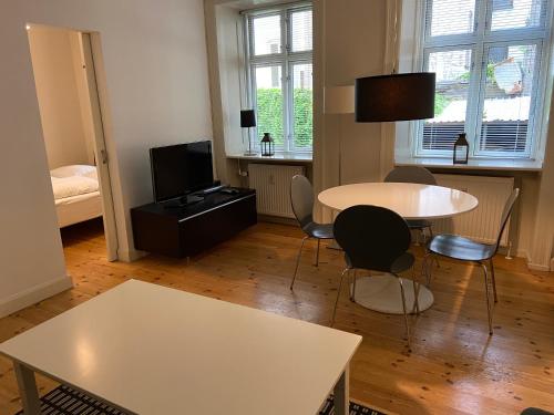 een woonkamer met een tafel en stoelen en een televisie bij City Apartments 114 in Kopenhagen