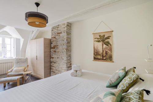 a bedroom with a large white bed and a chair at L'Armateur - Appartement intramuros - plage - St Malo in Saint Malo