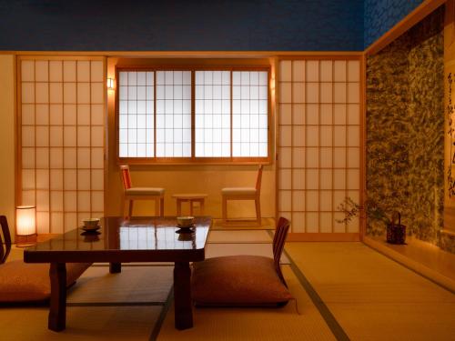 a room with a table and chairs and a window at Ryokan Kohro in Kyoto