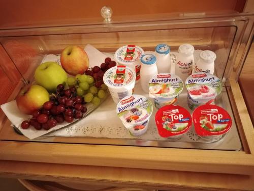 a tray of fruit and yogurt in a refrigerator at Hotel Garni Haus zum Gutenberg in Hallbergmoos