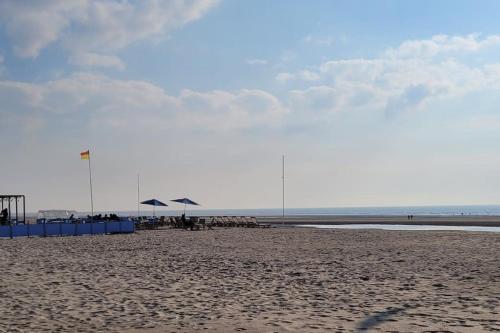 a beach with umbrellas and chairs on the sand at Calme et détente dans une maison proche de la mer in Neufchâtel-Hardelot