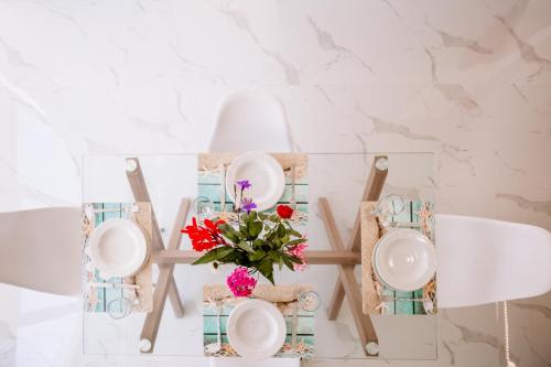 a table with plates and a vase of flowers at Nadia Apartments B in Kalamaki