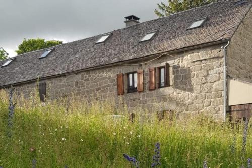 een oud stenen gebouw met ramen in een veld bij Appartement 6 pers sur l'Aubrac 