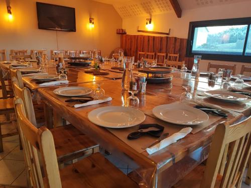 a large wooden table with plates and glasses on it at Auberge du Col du Festre in Le Dévoluy