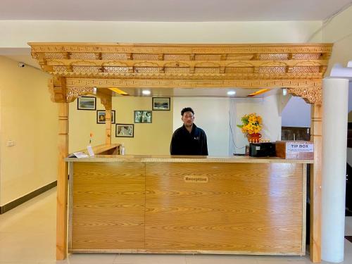 a man standing behind a counter in front of a mirror at Hotel Palam Hills in Leh