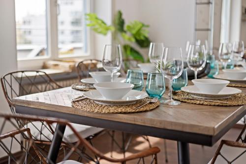 a wooden table with glasses and plates on it at Arbio I Premium Penthouse Apartment Augsburg in Augsburg
