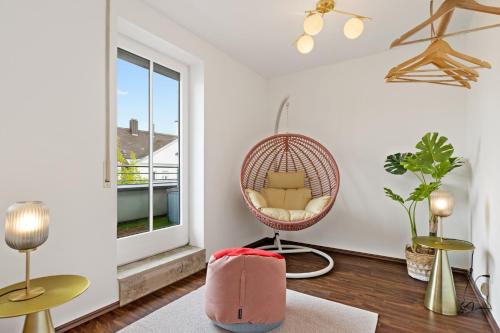 a room with a rattan chair and a window at Arbio I Premium Penthouse Apartment Augsburg in Augsburg