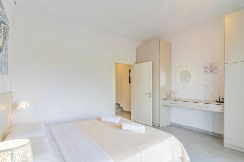 a white bedroom with a bed and a kitchen at Seashell by halu! in Nea Fokea