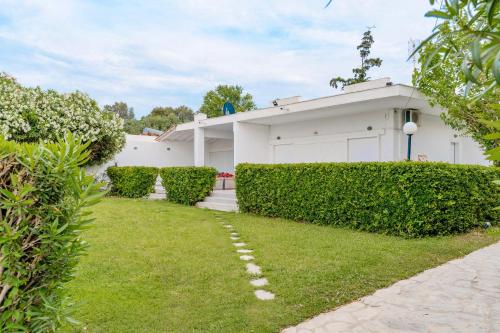 a white house with hedges in front of a yard at Seashell by halu! in Nea Fokea