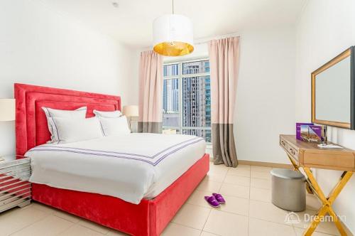 um quarto com uma cama vermelha, uma secretária e uma janela em Dream Inn Apartments - Burj Views em Dubai